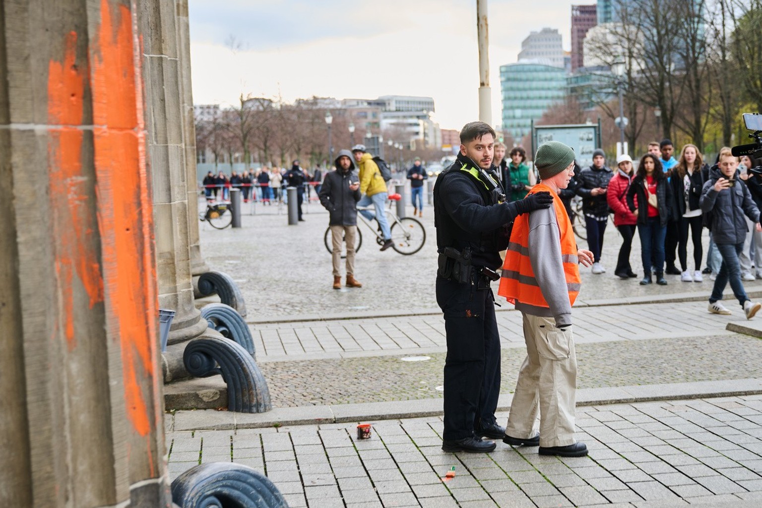 16.11.2023, Berlin: Ein Polizeibeamter (Mitte l) nimmt eine Klimaaktivistin in Gewahrsam, die das Brandenburger Tor mit oranger Farbe bemalt hat. Die Gruppe Letzte Generation teilte am Donnerstag mit, ...