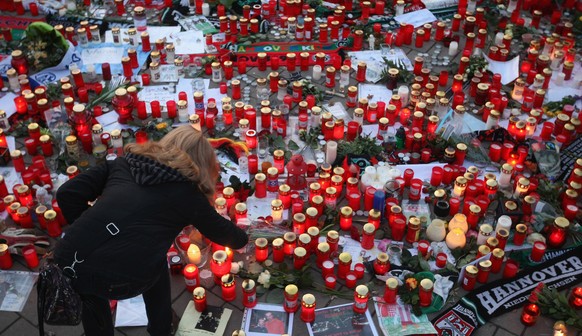 HANOVER, GERMANY - NOVEMBER 15: A fan of the Hannover 96 football club lights a candle among a sea of candles for goalie Robert Enke shortly before a memorial service prior to Enke?s funeral at AWD Ar ...