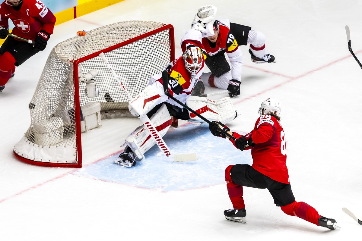epa12125919 Switzerland's forward Christoph Bertschy, right, scores the 1:0 against Austria's goaltender David Kickert #30, during the 2025 IIHF Ice Hockey World Championship quarter final m ...