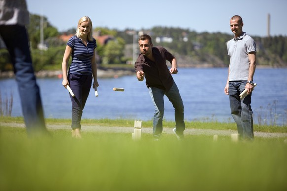 Eine Gruppe Menschen spielt Kubb (Wikingerschach) auf einer Wiese