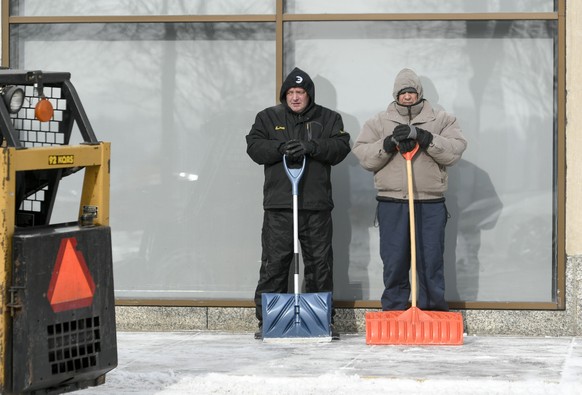 epaselect epa07334670 Workers take a break from clearing snow from downtown sidewalks while schools and some government offices remain closed for a third day due to the extreme cold weather, in St. Pa ...