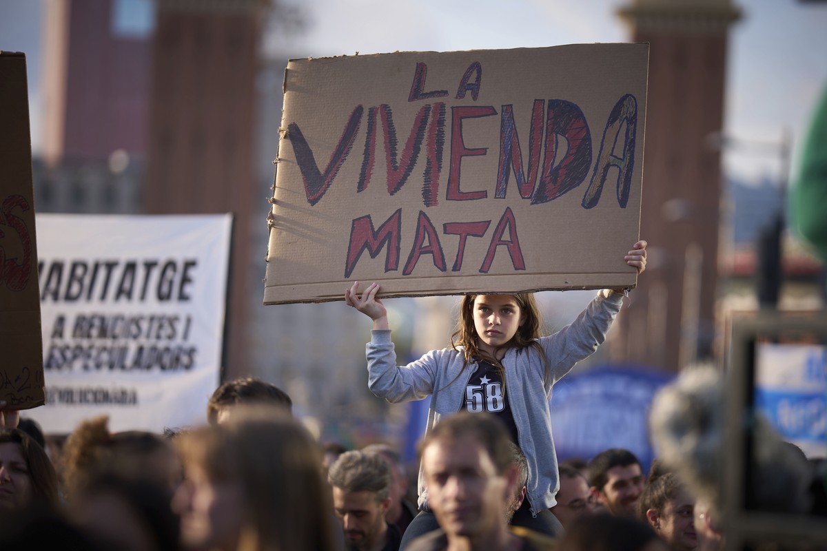 A girl holds a banner reading "housing killing" as people gather during a demonstration to protest high housing costs in Barcelona, Spain, Saturday, April 5, 2025. (AP Photo/Emilio Morenatti ...