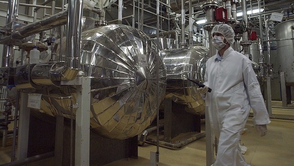 FILE - An Iranian security official in protective clothing walks through part of the Uranium Conversion Facility just outside the Iranian city of Isfahan, March 30, 2005. (AP Photo/Vahid Salemi, File) ...