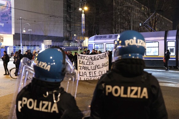 epa11187432 Riot police officers keep watch on a marching group following an attack on a police car in front of the police headquarters in Turin, northern Italy, 28 February 2024. A group of autonomis ...