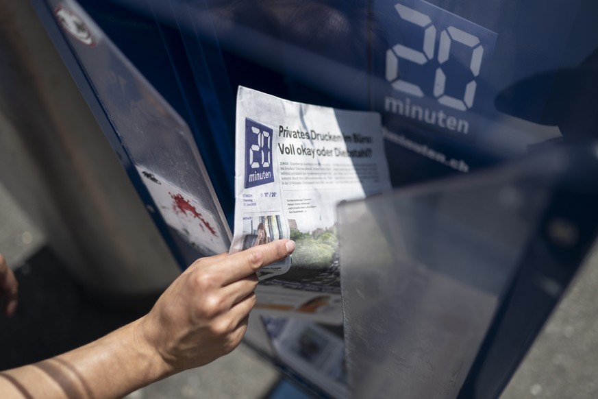 Eine Frau greift die Printausgaben der Pendlerzeitung 20 Minuten, am Dienstag, 17. Juni 2025, in Zuerich. Wie der Herausgeber TX-Group heute informiert wird die Printausgabe von 20 Minuten per Ende 20 ...