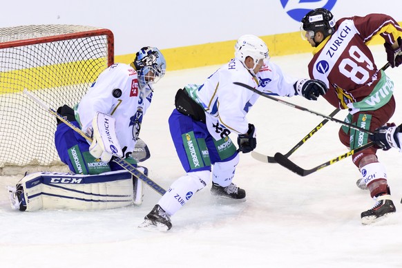 Le joueur zougois, Santeri Alatalo, centre, lutte pour le puck avec le joueur genevois, Cody Almond, droite, devant le gardien zougois, Tobias Stephan, gauche, lors du match de hockey sur glace de dem ...