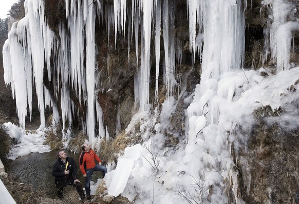 epa05708907 Two men look at the icicles hanging from a waterfall in Roncal, province of Navarra, Spain, 10 January 2017. The State Meteorological Agency (Aemet) has forecast strong winds, snowfalls an ...