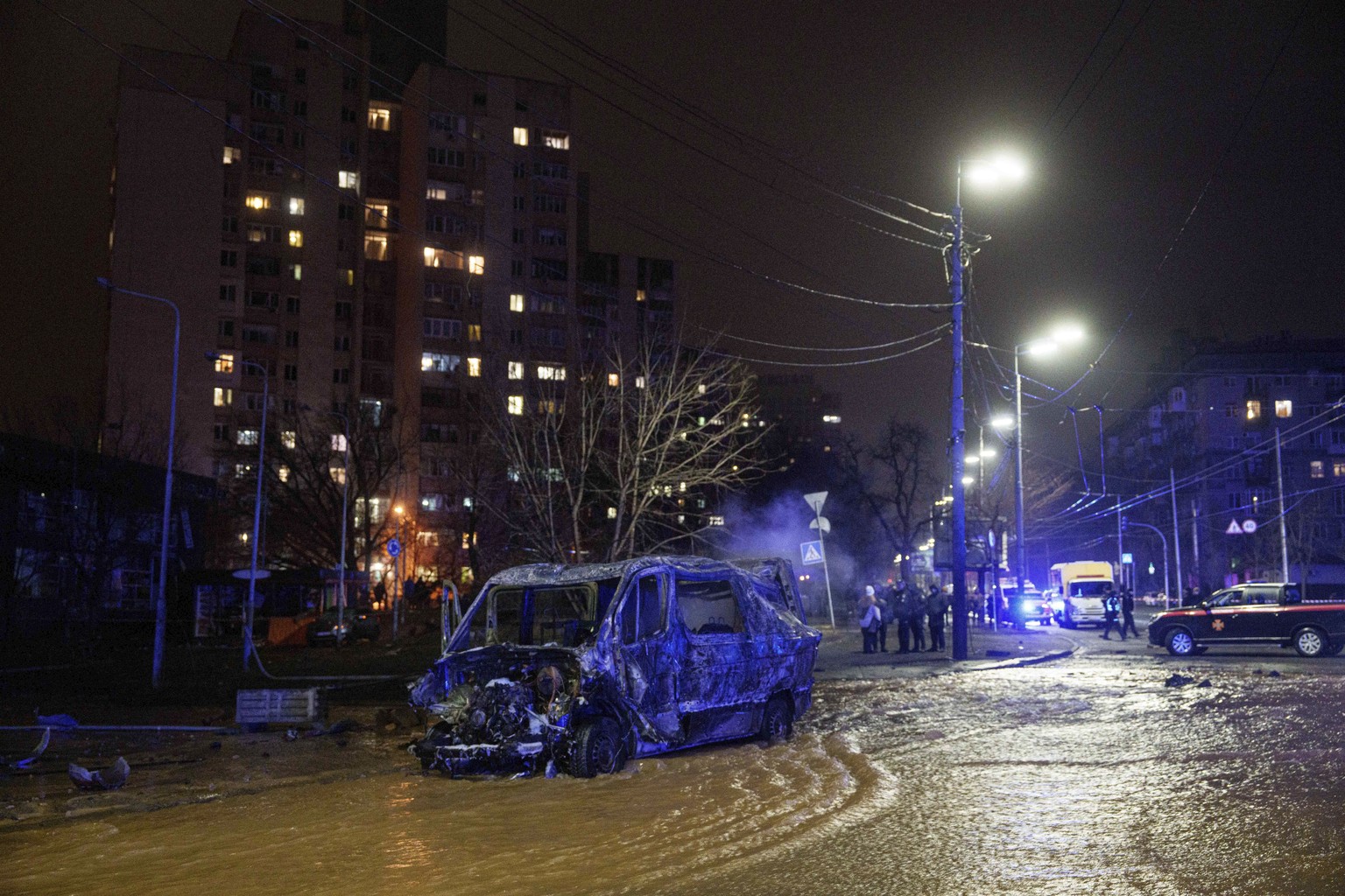 A destroyed minivan with two dead bodies inside is seen on a street flooded after a Russian missile strike on Kyiv, Ukraine, Saturday, Jan. 18, 2024. (AP Photo/Evgeniy Maloletka)