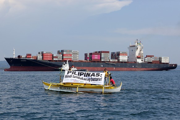 Die «MV Bavaria» verlässt Subic Bay, im Vordergrund ein Greenpeace-Boot mit Protestplakat. 