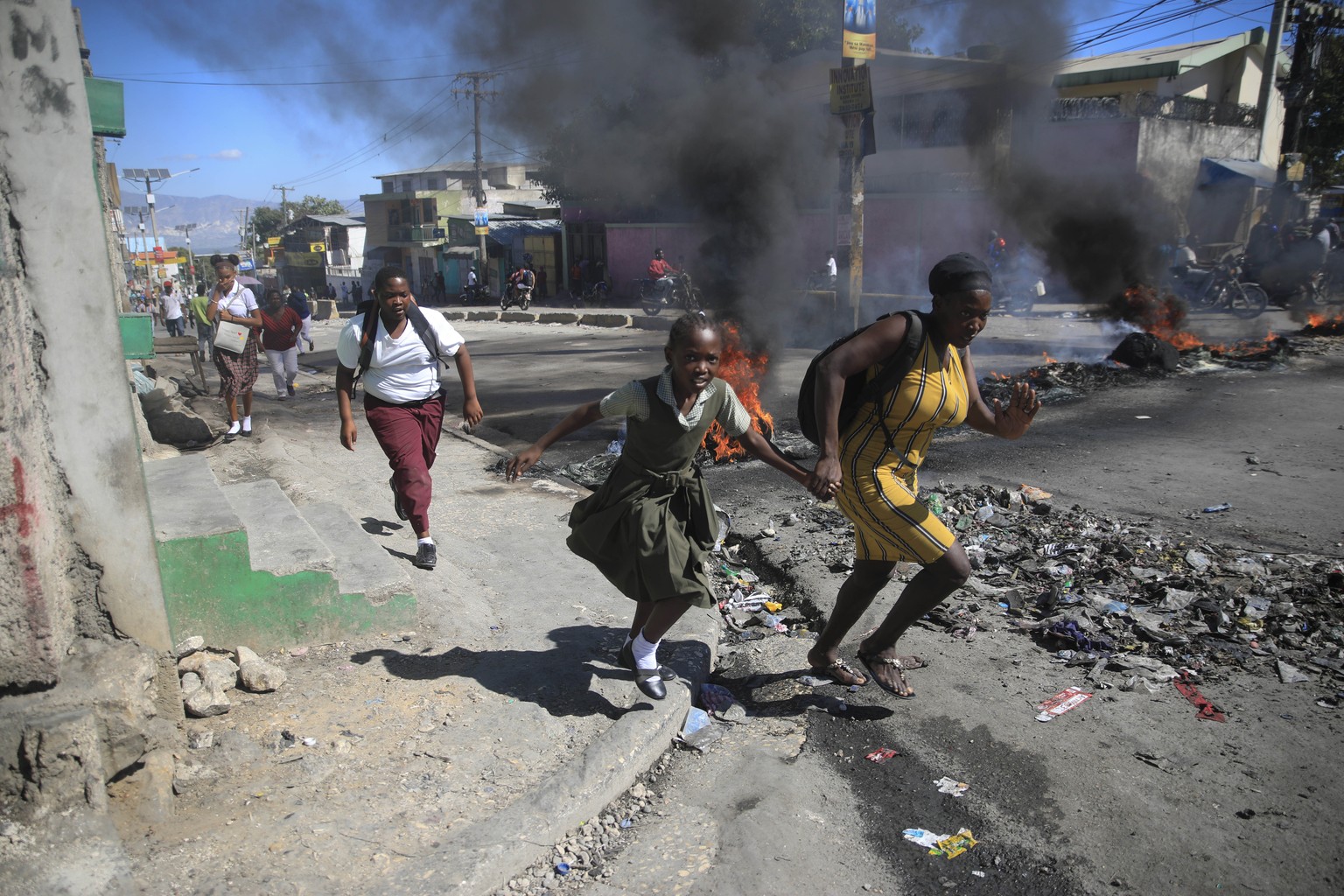 Ein Leben in ständiger Angst: Eine Mutter rennt mit ihrer Tochter durch die Strassen von Port-au-Prince, wo die lokale Polizei Barrikaden errichtet hat.