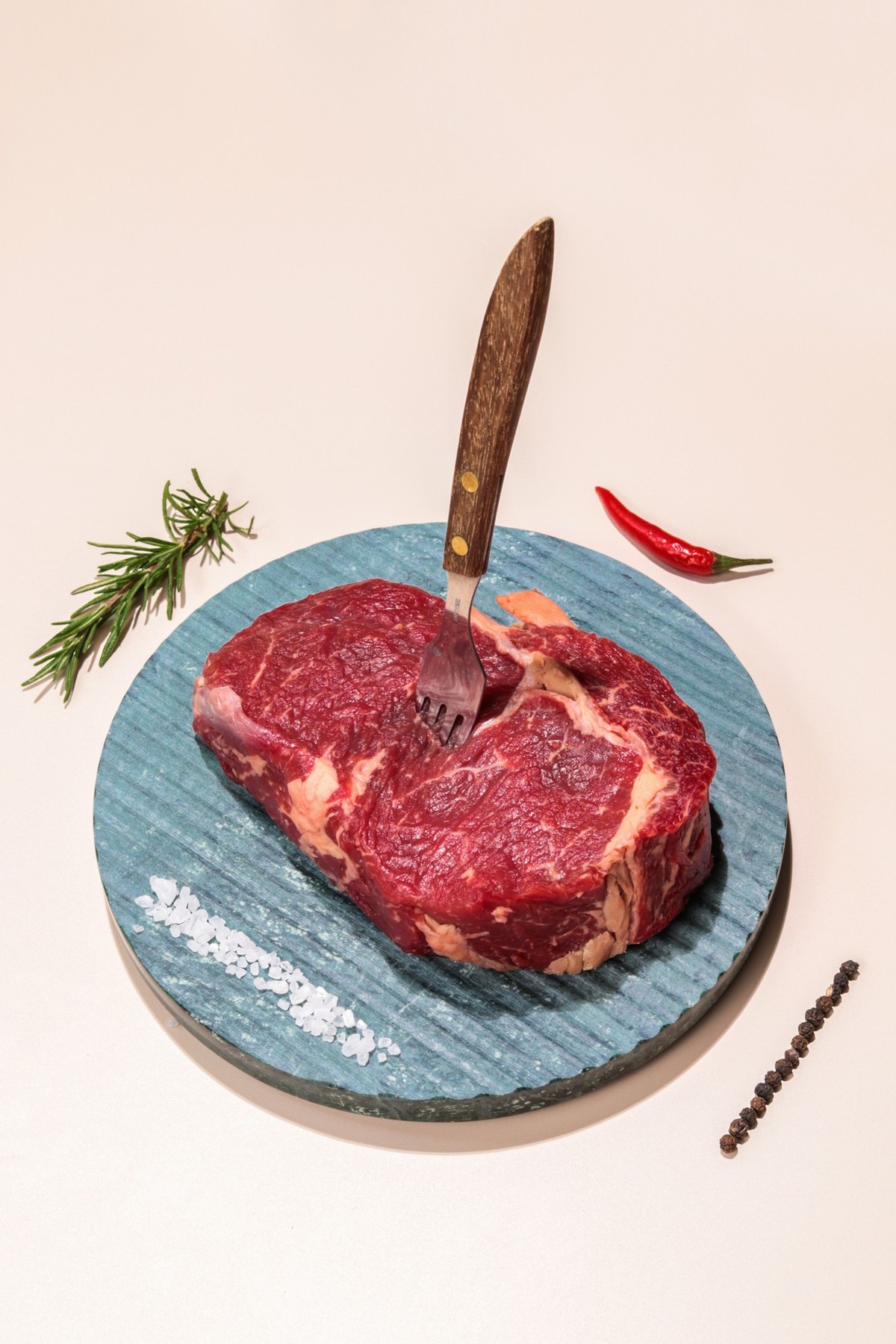 Raw Beef Steak meat on plate with fork and spices on colorful background