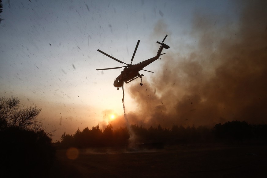 epa09398560 A firefighting helicopter douses a wildfire in the area of Drossopigi, Varybobi, northeastern suburb of Athens, Greece, 05 August 2021. More firefighters and support by air have been added ...