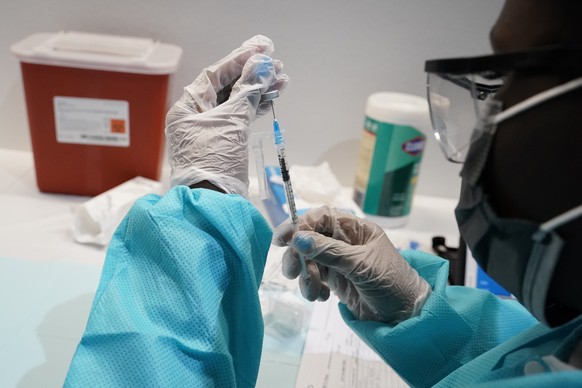 FILE - In this July 22, 2021, file photo, a health care worker fills a syringe with the Pfizer COVID-19 vaccine at the American Museum of Natural History in New York. About 100 of the more than 600 U.S. athletes descending on Tokyo for the Olympics are unvaccinated, the U.S. Olympic and Paralympic Committee's medical chief said hours before Opening Ceremony on Friday, July 23. (AP Photo/Mary Altaffer, File)