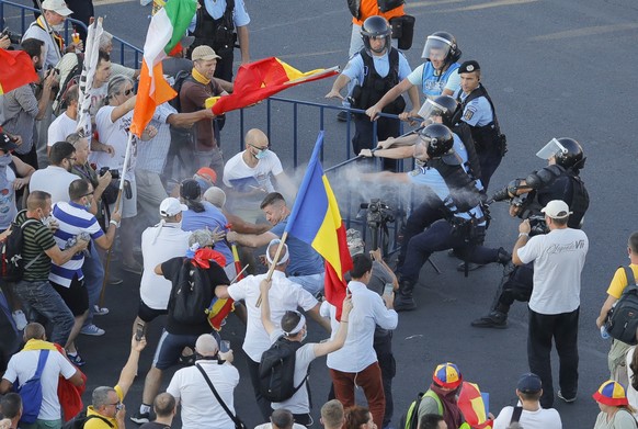 Riot police spray teargas while scuffling with protesters outside the government headquarters, in Bucharest, Romania, Friday, Aug. 10, 2018. Romanians who live abroad are staging an anti-government pr ...