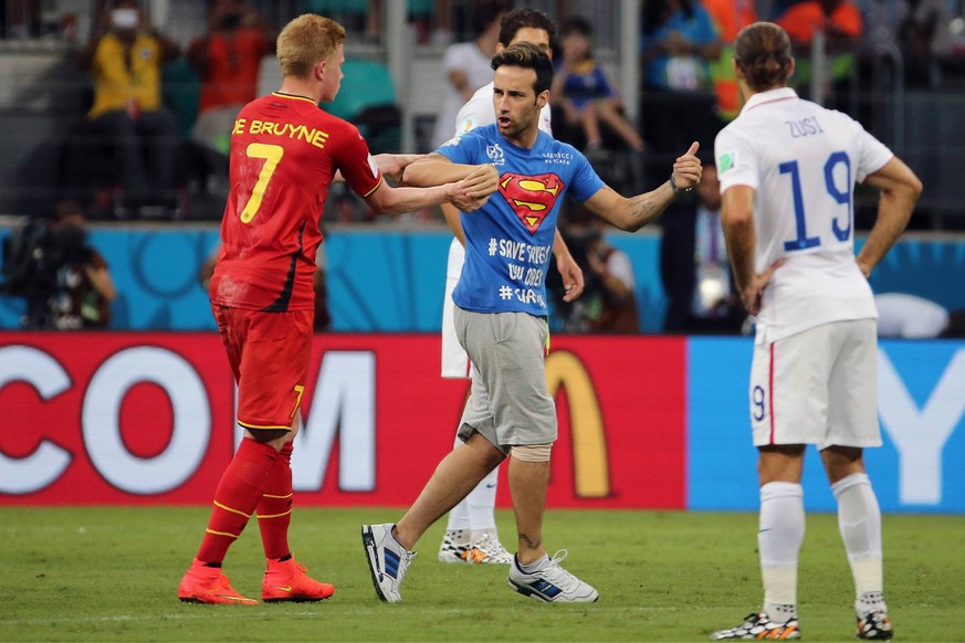 SALVADOR, BRASIL- JULIO 1: Kevin DE Bruyne (I) and Graham Zusi (r) geraten an den bekannten Flitzer Mario Ferri, der in seinem Superman T Shirt aus dem Rollstuhlbereich das Achtelfinale Belgien - USA  ...