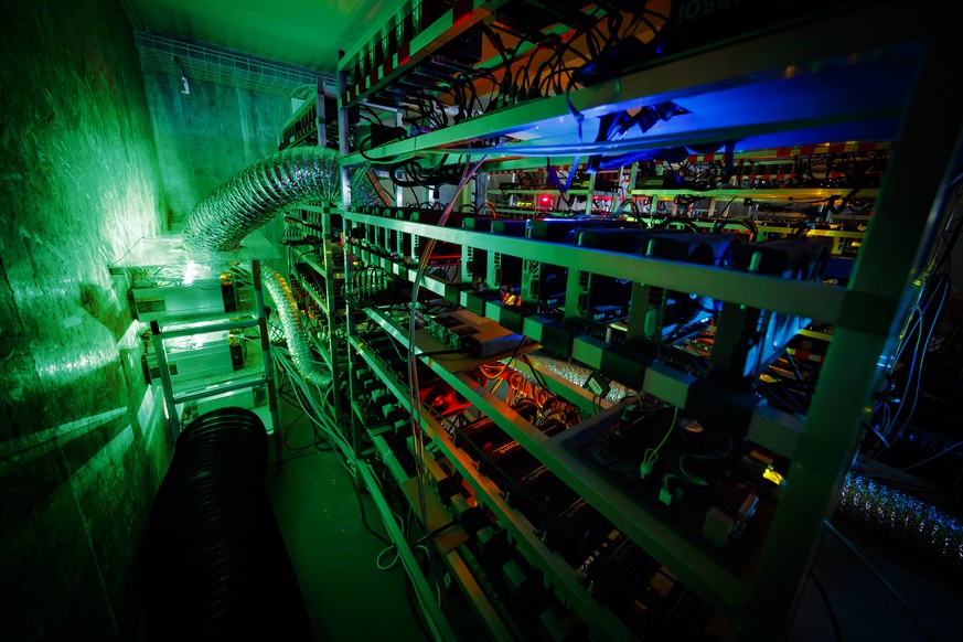 Racks of graphic cards and cryptocurrency mining equipment are lit by the LED status lights of electronic boards during a long exposure photograph at a cryptocurrency mine in the small alpine village  ...