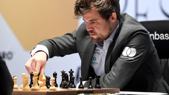 epa09633984 Defending Champion Magnus Carlsen of Norway plays against Ian Nepomniachtchi (not pictured) of Russia during the 11th round of FIDE World Chess Championship at the EXPO 2020 Dubai in Dubai ...