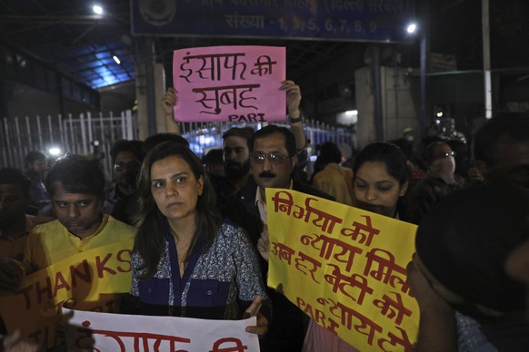 Indians holds banners and stand outside Tihar central prison where four men were sentenced to capital punishment in New Delhi, India, Friday, March 20, 2020. Four men sentenced to death for the grueso ...