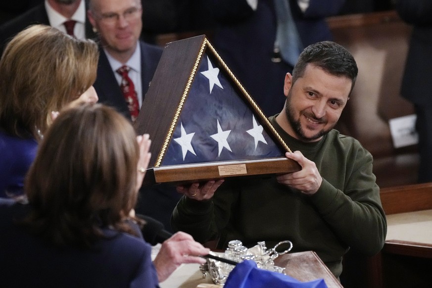 Ukrainian President Volodymyr Zelenskyy holds an American flag that was gifted to him by House Speaker Nancy Pelosi of Calif., after he addressed a joint meeting of Congress on Capitol Hill in Washing ...