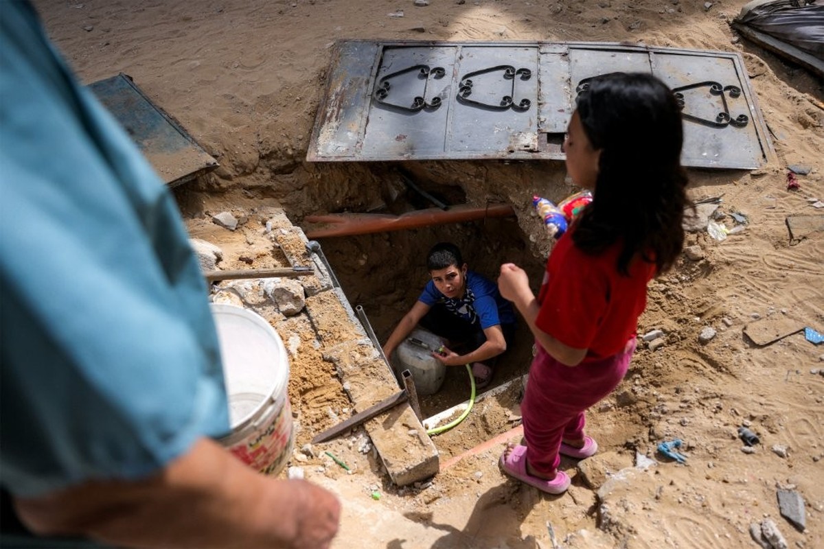 Un garçon remplit des récipients avec l'eau qui reste dans les canalisations souterraines, à Beit Lahia, dans le nord de la bande de Gaza.