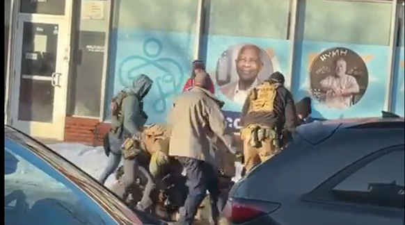 Die Situation ist unübersichtlich, aber: Es sind mehrere Beamte, die den bisher nicht identifizierten Mann zu Boden drücken.