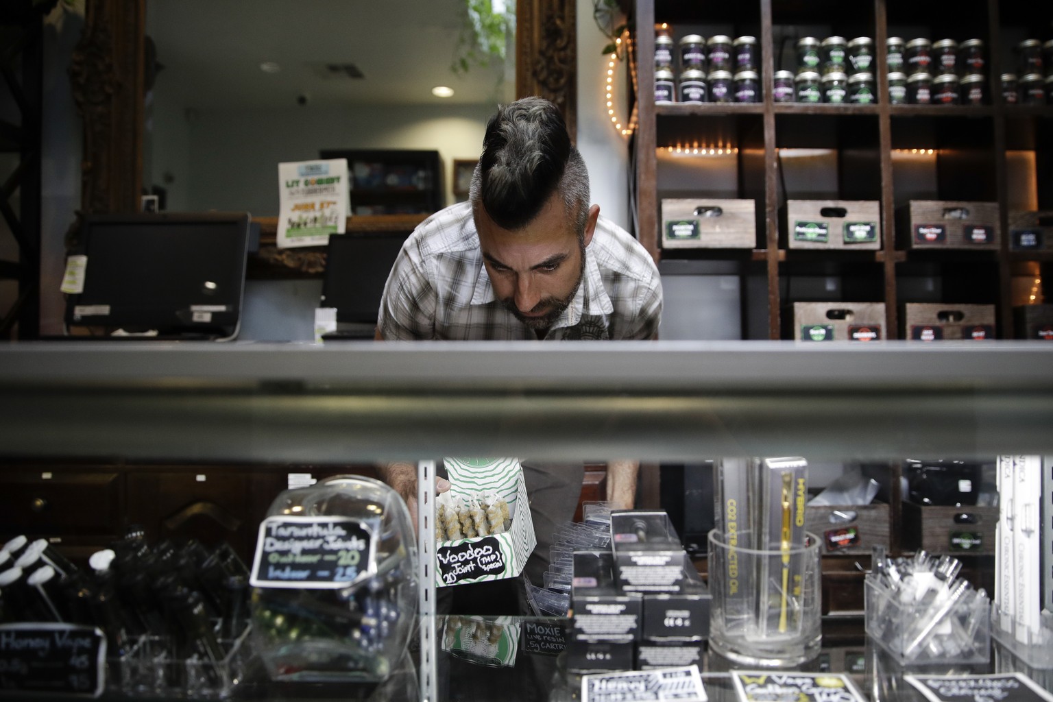 FILE - In this June 27, 2017, file photo, Jerred Kiloh, owner of the Higher Path medical marijuana dispensary, stocks shelves with with cannabis products in Los Angeles. Several marijuana businesses i ...