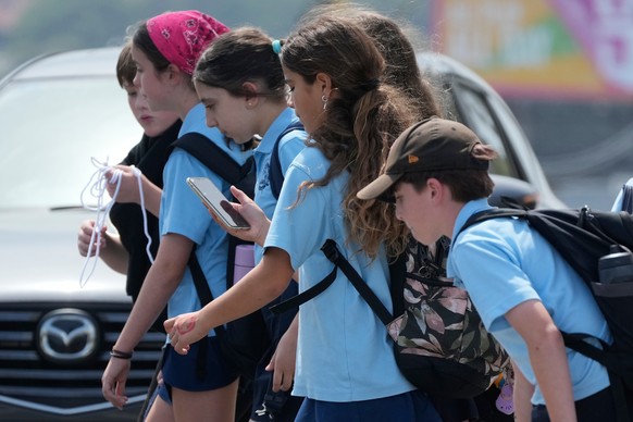 A school girl uses her phone as she walks with a group of kids in Sydney, Monday, Dec. 8, 2025. (AP Photo/Rick Rycroft)
Australia Social Media Ban
