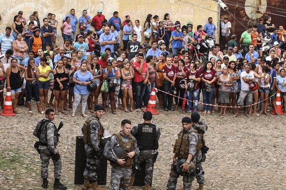 epa06484584 Relatives and friends of inmates wait in front of an area cordoned-off by the police in Itapaje, Brazil, 29 January 2018. At least 10 inmates were killed when prisoners of rival gangs clas ...