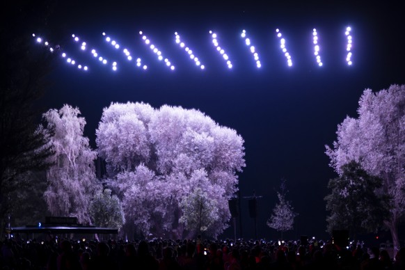 Des personnes regardent un spectacle de drones depuis les bords du lac de Bienne, ce dimanche 31 juillet 2022 a Bienne. Cette choregraphie aerienne remplace les traditionnelles feux d&#039;artifice du ...