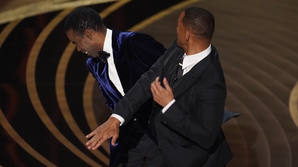 Will Smith, right, hits presenter Chris Rock on stage while presenting the award for best documentary feature at the Oscars on Sunday, March 27, 2022, at the Dolby Theatre in Los Angeles. (AP Photo/Ch ...