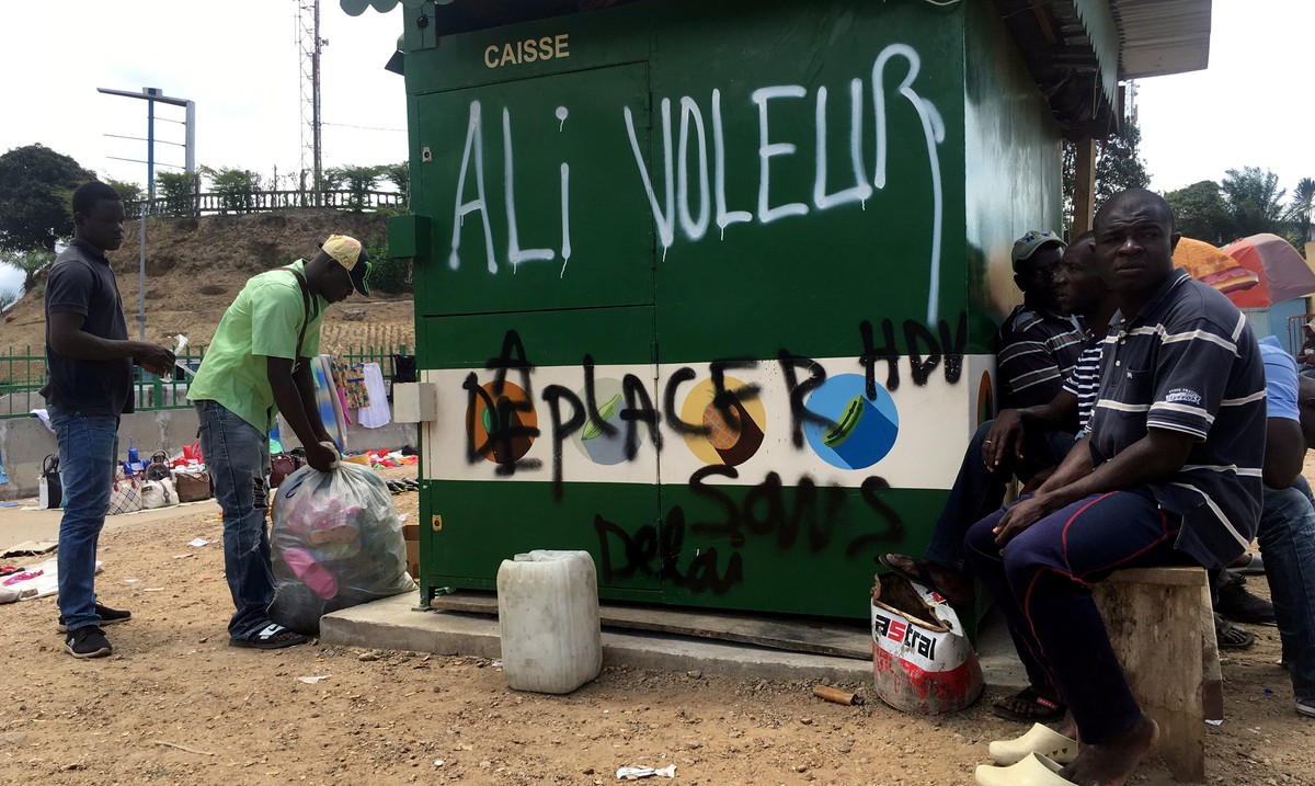 People sit next to graffiti that reads "Ali Thief", referring to incumbent President Ali Bongo, in Libreville, Gabon, September 24, 2016. Picture taken September 24, 2016. REUTERS/Marco Truj ...