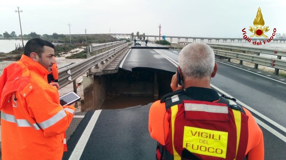 Firefighters stand next to a damaged bridge on the Santa Lucia stream along the road from Cagliari to Capoterra village, on the Sardinia island, Italy, Wednesday, Oct. 10, 2018. Torrential rains have  ...