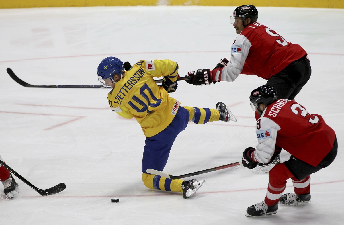 Sweden's Elias Pettersson, left, checks Austria's Thomas Raffl and Peter Schneider, right, during the Ice Hockey World Championships group B match between Sweden and Austria at the Ondrej Ne ...