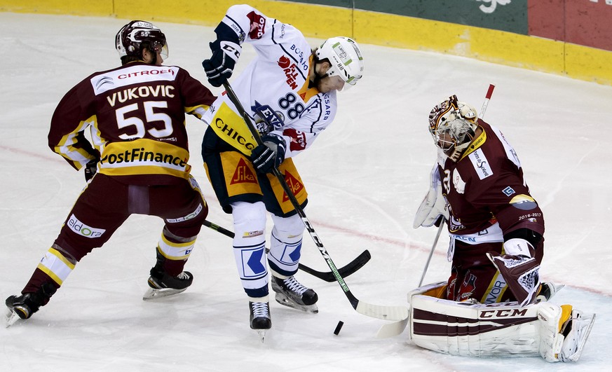 Zug&#039;s forward Sven Senteler, center, vies for the puck with Geneve-Servette&#039;s defender Daniel Vukovic, left, and Geneve-Servette&#039;s goaltender Robert Mayer, right, during the second leg  ...