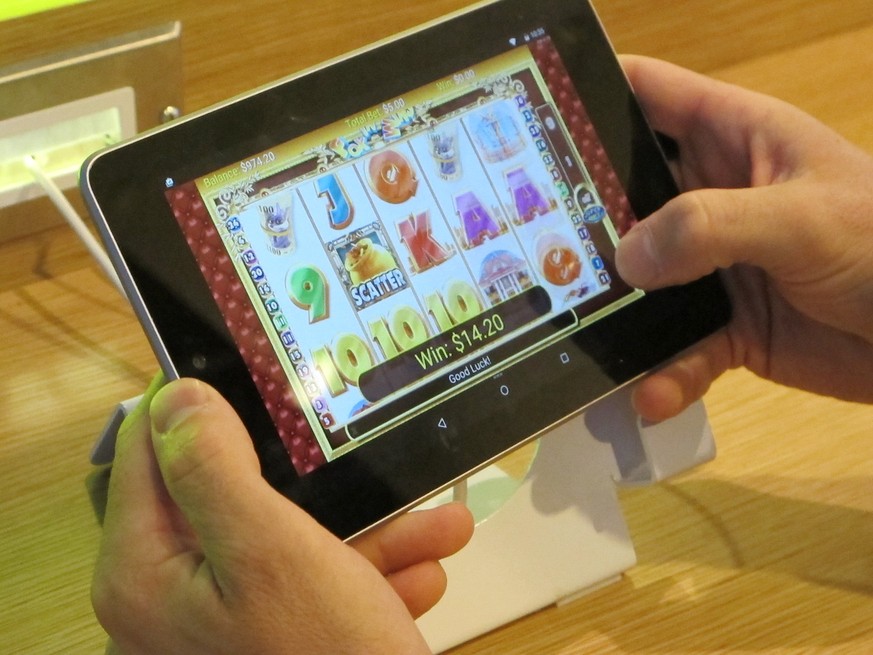 In this April 15, 2015 photo, an employee at Resorts Casino Hotel tries a touch-screen tablet device in the Atlantic City, N.J. casino&#039;s new Internet gambling lounge. The room is designed to help ...