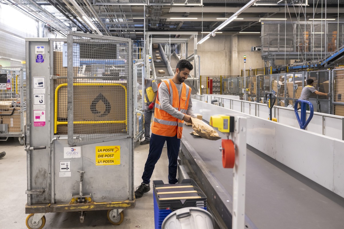 Hakim Mustafa legt Pakete aus Rollbehaeltern auf ein Foerderband im neuen Paketzentrum in Haerkingen, am Montag, 25. September 2023. Erstmalig hat die Schweizerische Post eine reine Paketsortieranlage ...