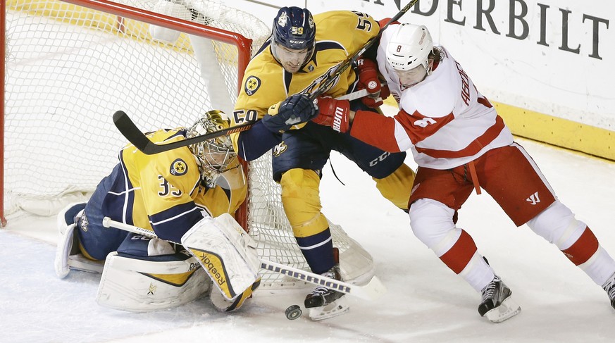 Nashville Predators goalie Pekka Rinne (35), of Finland, reaches for the puck as Predators defenseman Roman Josi (59), of Switzerland, tries to block Detroit Red Wings left wing Justin Abdelkader (8)  ...