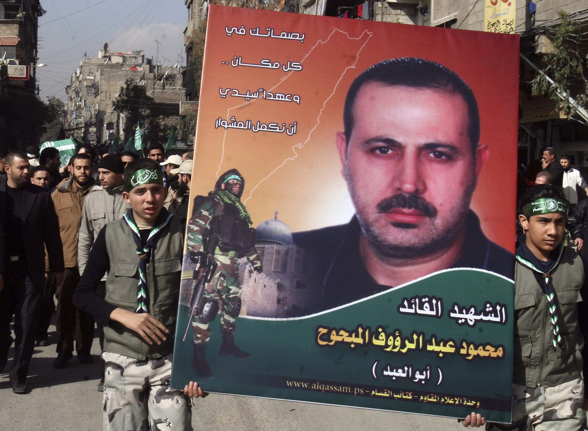 Palestinians carry a picture of Mahmoud al-Mabhouh, one of the founders of Hamas' military wing, as others carry his coffin, left, during his funeral procession at the Palestinian refugee camp of ...