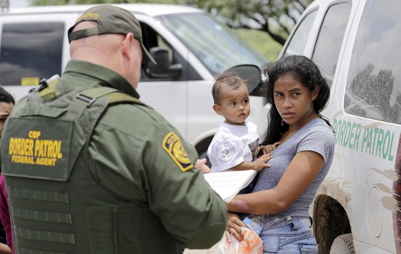 FILE - In this June 25, 2018, file photo, a mother migrating from Honduras holds her 1-year-old child as surrendering to U.S. Border Patrol agents after illegally crossing the border near McAllen, Tex ...