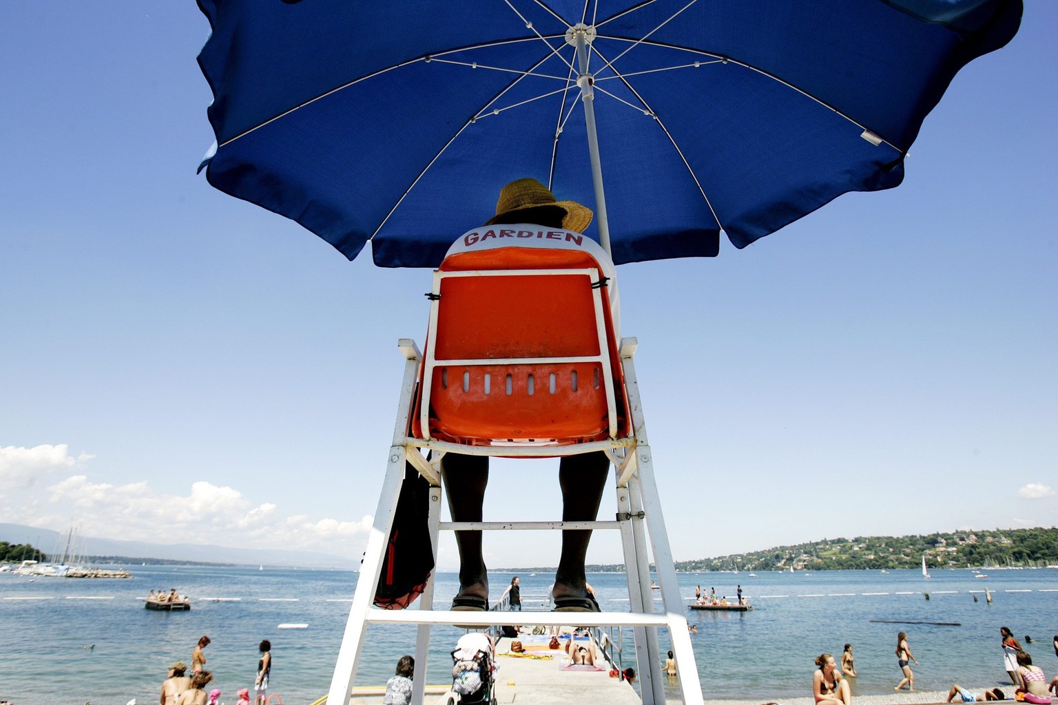 A pool attendant looks at people enjoying the warm and sunny weather at the public swimming pool "Bains des Paquis" at the lake of Geneva, in Geneva, Switzerland, Friday, June 20, 2008. (KEY ...