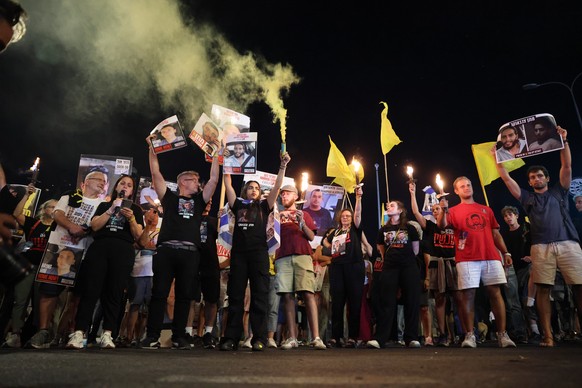 epa12288757 Families and supporters of Israeli hostages held by Hamas in Gaza carrying flares, banners and pictures of the hostages protest outside the Israeli Prime Minister&#039;s office during a se ...