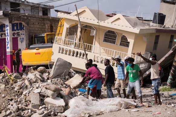 epa09423987 Peope attempt a rescue after 7.2 earthquake that occurred on 14 August, in Les Cayes, Haiti, 21 August 2021. The earthquake left some 2,200 dead and 12,000 wounded. EPA/ORLANDO BARRIA