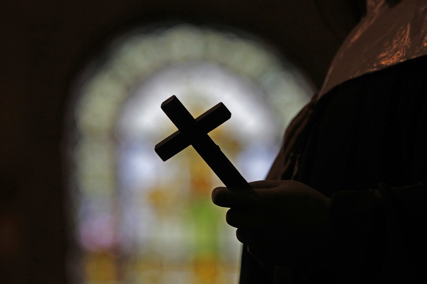 FILE - This Dec. 1, 2012 file photo shows a silhouette of a crucifix and a stained glass window inside a Catholic Church in New Orleans. As U.S. Catholic bishops gather for an important national assem ...