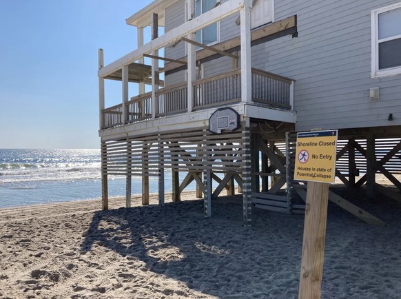 Ein Verbotsschild in Rodanthe (North Carolina) warnt Menschen, die am Strand spazieren, vor der möglichen Einsturzgefahr eines Ferienhauses.