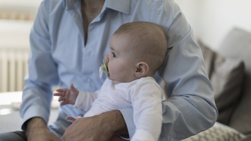 ZUM THEMA VATERSCHAFTSURLAUB STELLEN WIR IHNEN HEUTE, MITTWOCH, 25. OKTOBER 2017, FOLGENDES BILDMATERIAL ZUR VERFUEGUNG --- A father sits on the sofa with his five-month-old daughter, pictured in Kilc ...