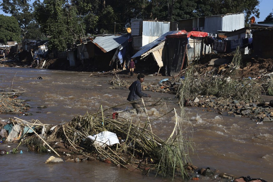 A man crosses a river at an informal settlement during flooding in Durban, South Africa, Thursday, April 14, 2022. Heavy rains and flooding have killed at least 341 people in South Africa&#039;s easte ...
