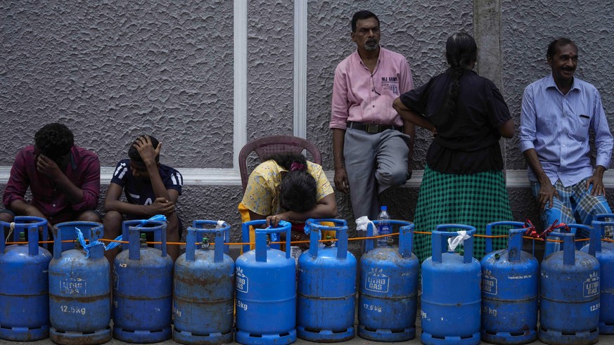 People wait in a queue expecting to buy cooking gas near a distribution center in Colombo, Sri Lanka, Tuesday, July 12, 2022. Facing severe shortages of food, fuel and medicine, protesters on Saturday ...