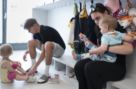 THEMENBILD ZUR LANCIERUNG DER KITA-INITIATIVE --- Betreuungspersonal hilft Kleinkindern beim Anziehen der Schuhe und Sonnenschutzkleidung, bevor es zum Spielen in den Aussenbereich der Kita 6a der Sti ...