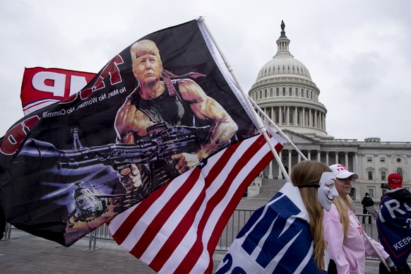 epa08920980 Pro-Trump protesters pass the US Capitol Building carrying flags, including one flag that depicts US President Trump as Rambo, in Washington, DC, USA, 05 January 2021. Right-wing conservat ...