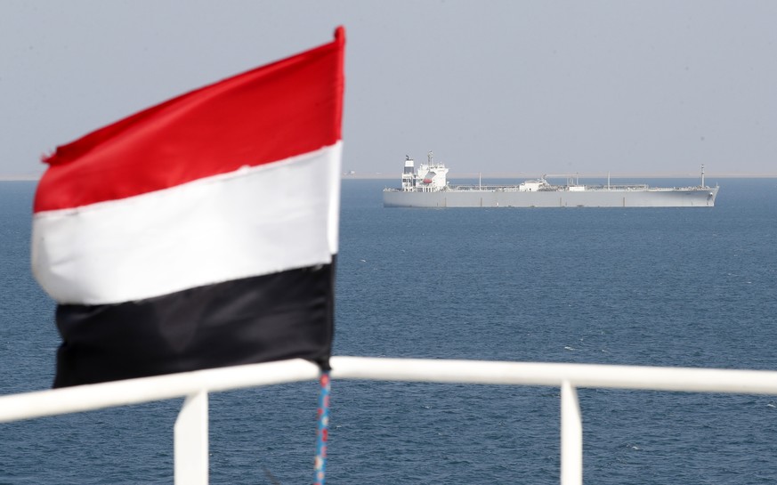 epa11014294 A ship sails offshore of the Al-Salif port as a Yemeni flag flutters on the deck of the Galaxy Leader cargo ship, seized by the Houthis, on the Red Sea in the province of Hodeidah, Yemen,  ...